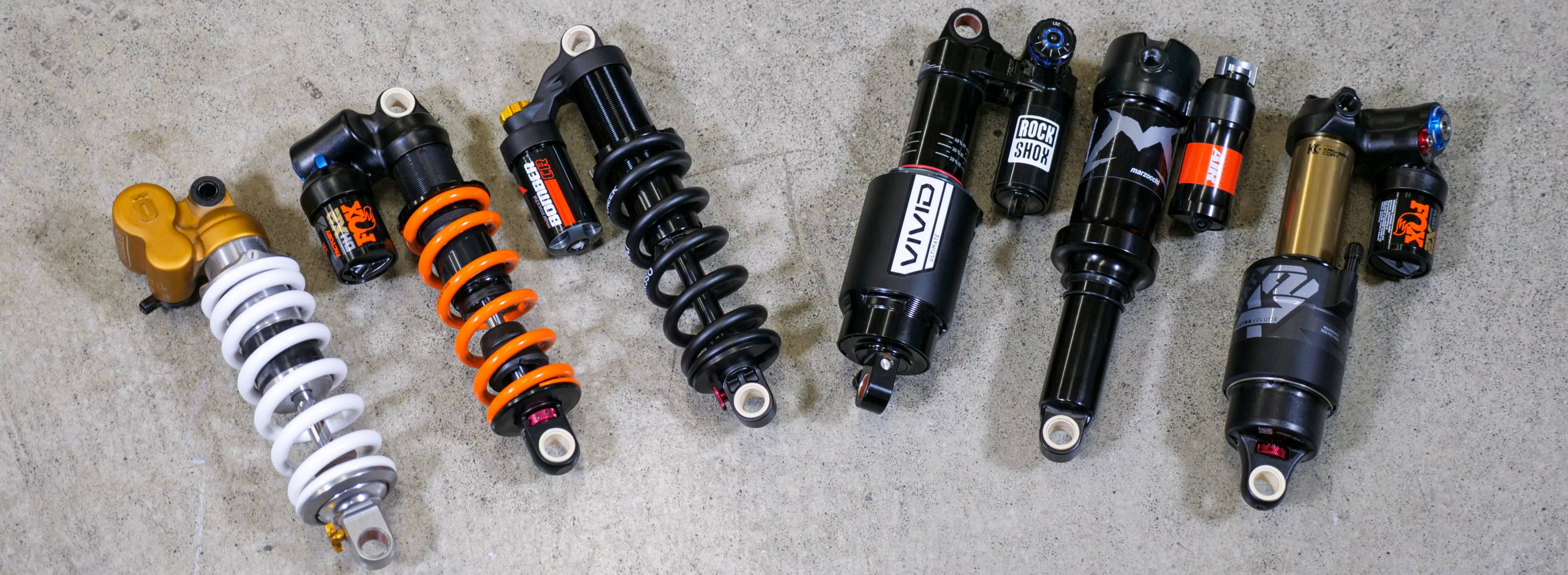 a bunch of air and coil rear mountain bike shocks laying on the ground