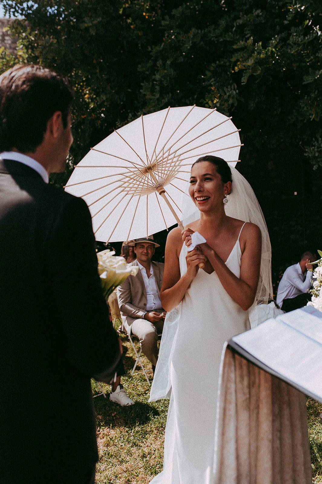 Braut hält weißen und hölzernen Regenschirm am Altar