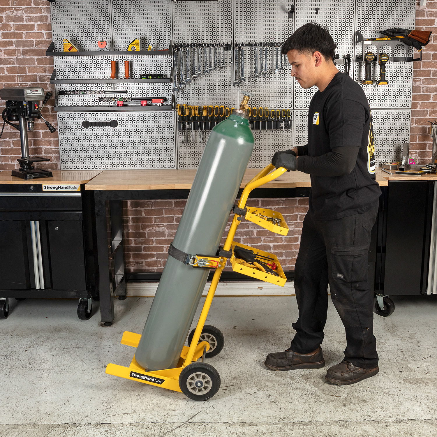 Person using a cart to move a large gas cylinder in a workshop.