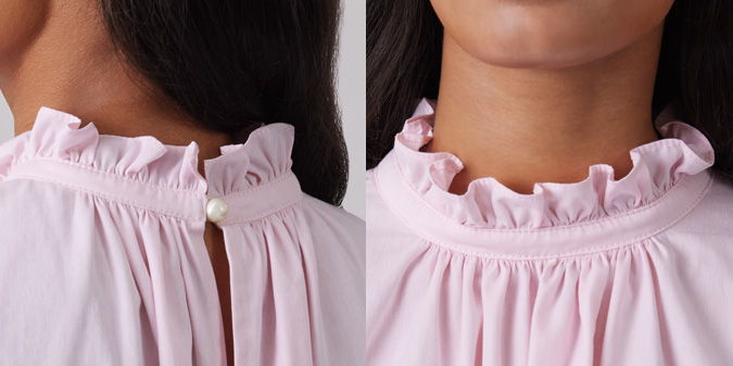 Close-up of a pink blouse with ruffled collar and pearl button detail.