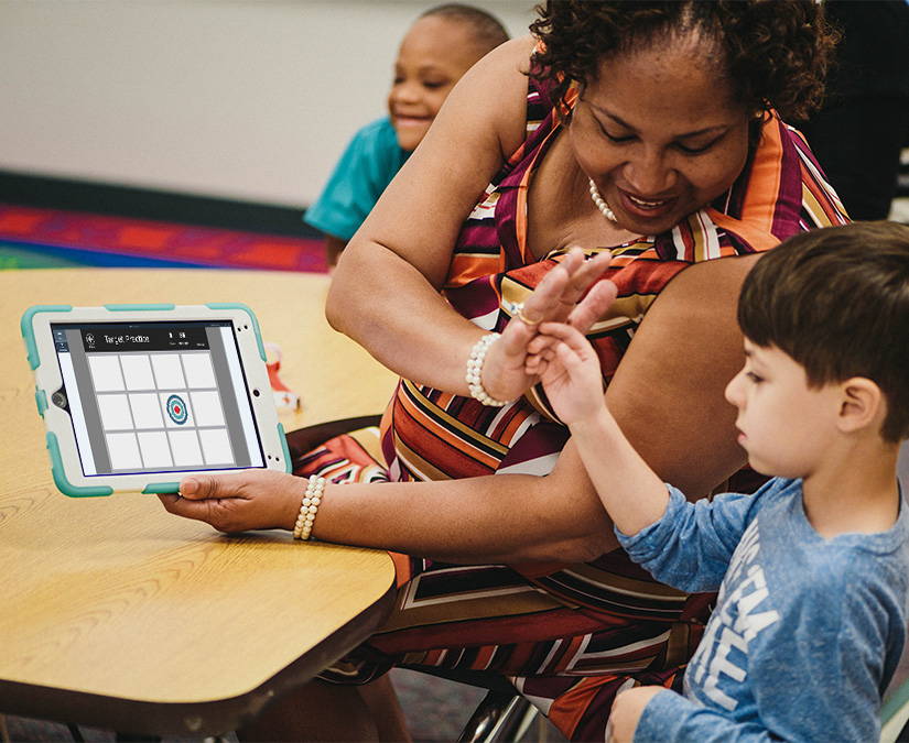 Special ed teacher showing Boardmaker 7 activity to a student on a Tobii Dynavox assistive technology device. 