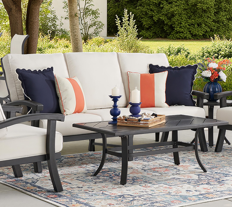 Outdoor seating area with cushions, coffee table, and decorative accessories.