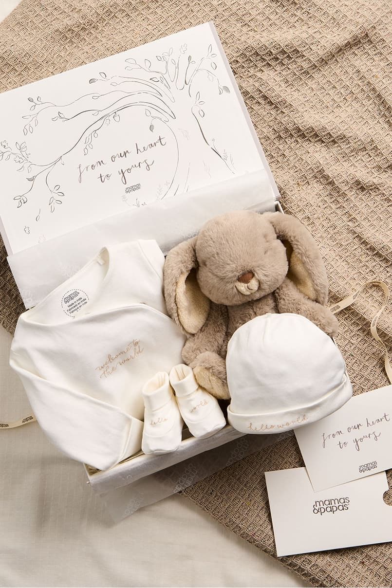 Baby gift box with clothing, a stuffed bunny, and a card.