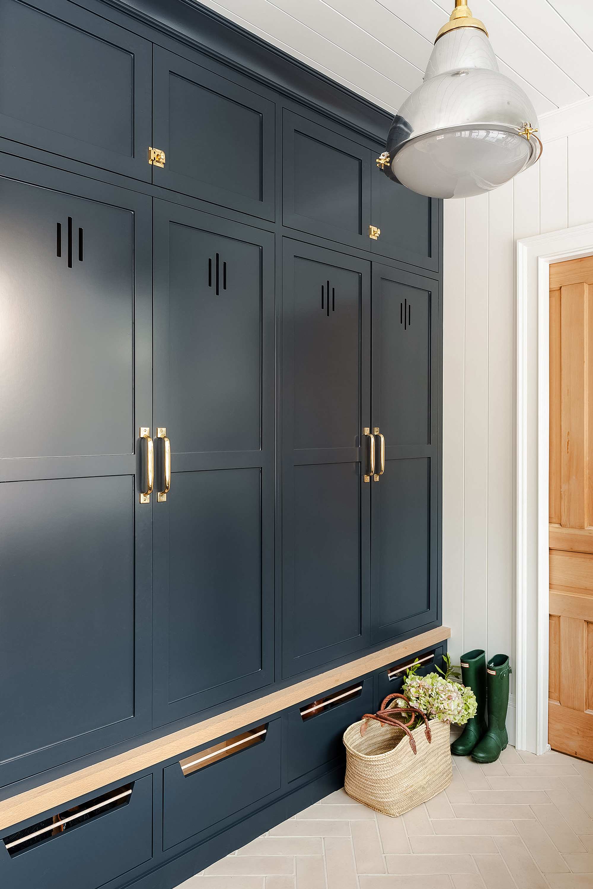 Timeless mudroom design by Studio McGee with dark navy cabinetry, brass hardware, and wood flooring