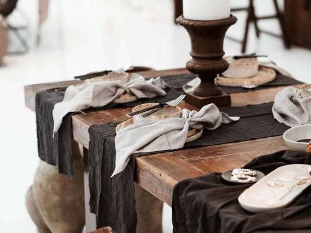 Assiettes et bols sur une table en bois avec des serviettes grises et des chemins de table noirs