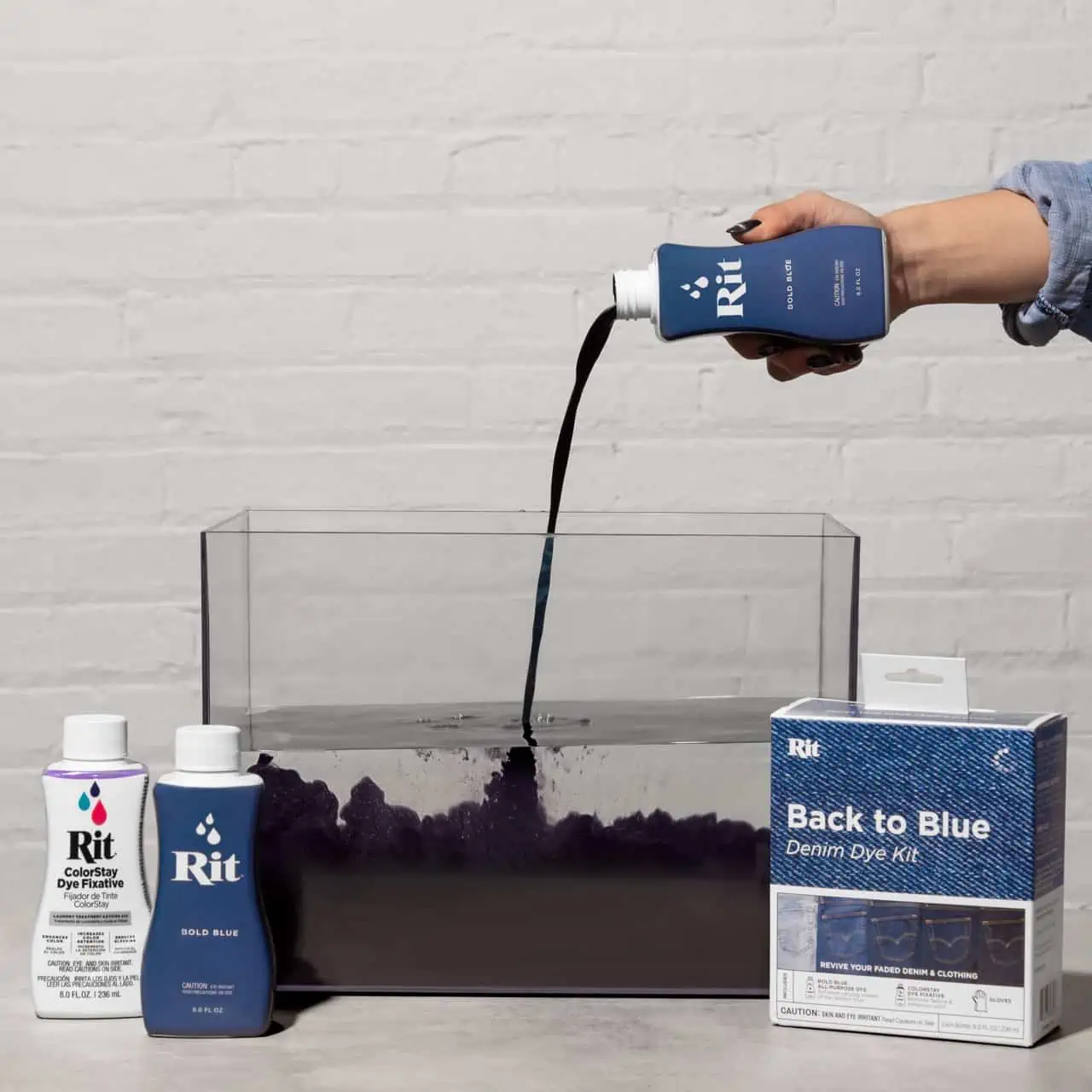 Person pouring blue dye into a container with dye products nearby.