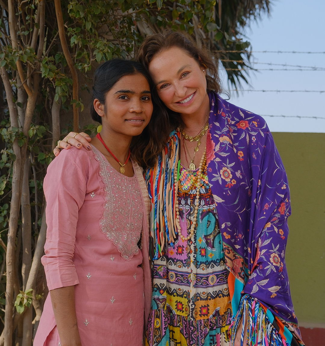 Camilla Franks, Founder and Creative Director, smiles beside a girl in a pink tunic from The Hunger Project's Adolescent Girls Program.