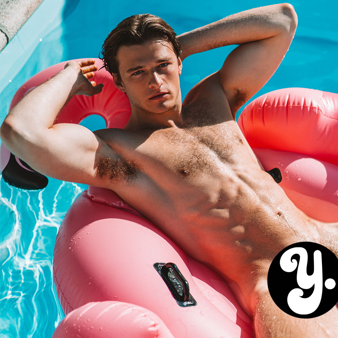 Young man lounging on a pink float in a swimming pool.