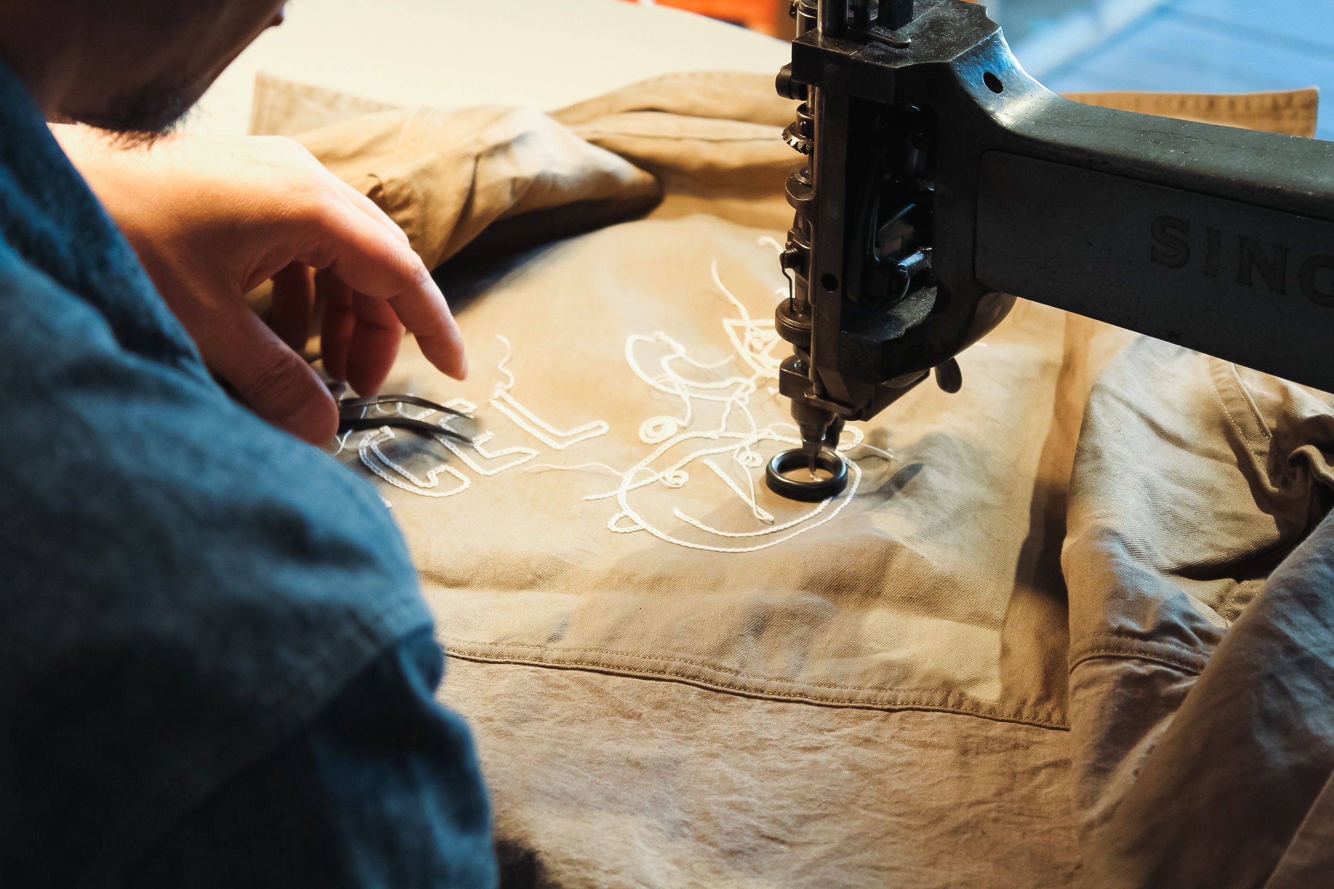 Person sewing intricate design onto fabric using a sewing machine.