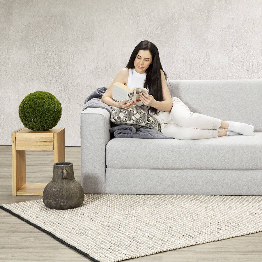 A young model reading a book on a new Zeek sofa bed.