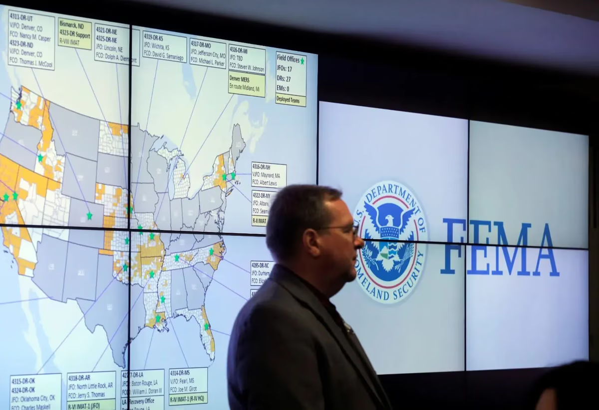 Man standing in front of FEMA presentation screens and maps.