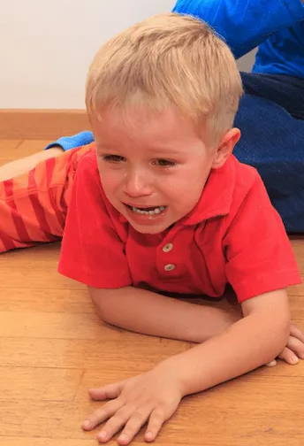 Image of young blonde haired child in red t-shirt looking upset and crying