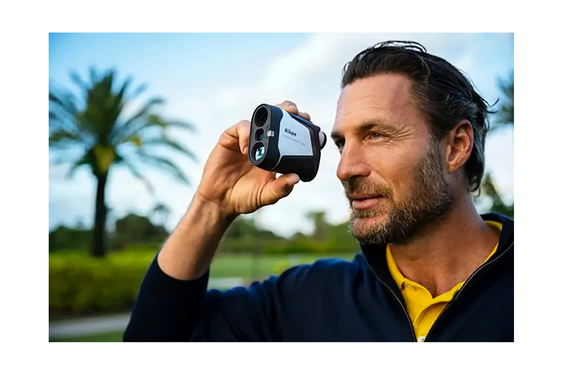 A golfer looking through the Nikon COOLSHOT 50i golf laser rangefinder on the golf course