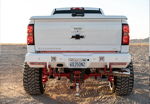 Rear view of lifted white Silverado 2500HD with red suspension thumbnail