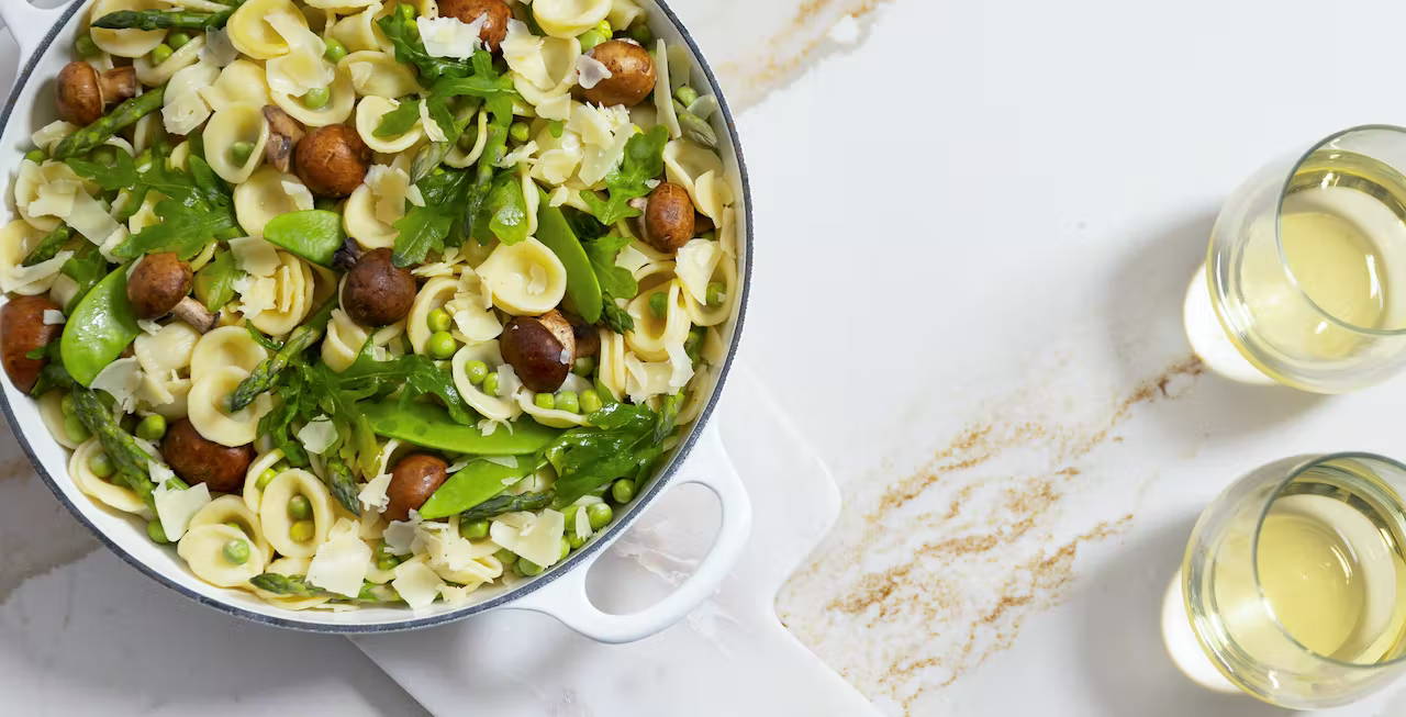 Spring Veggie Orecchiette on counter with two glasses of wine