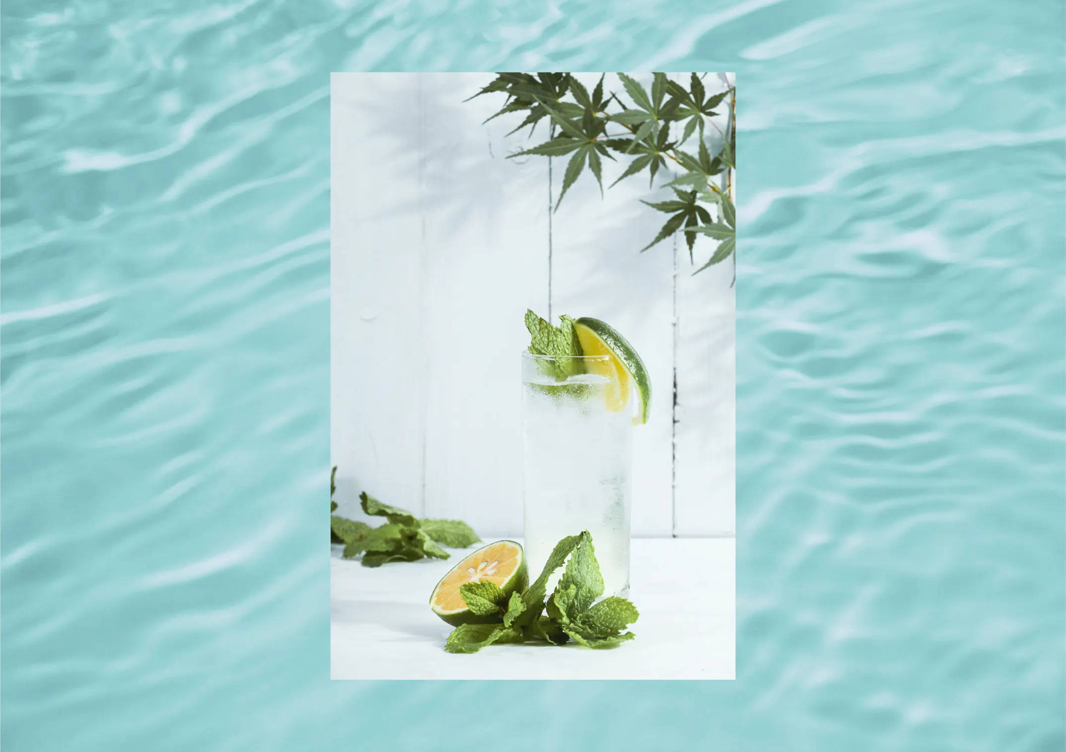 an iced tea mojito with fresh lime and mint garnish placed in front of a blue water background 