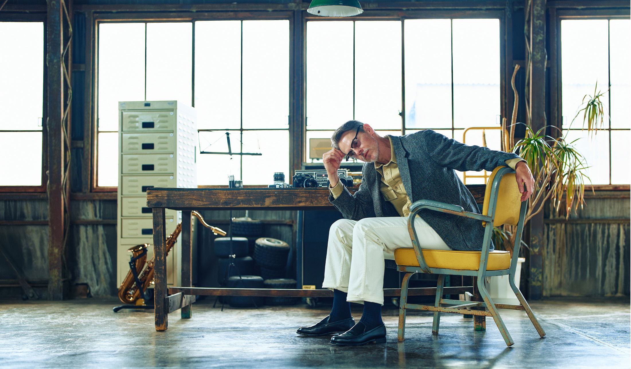 Person sitting in a chair, looking pensive in a bright office space.