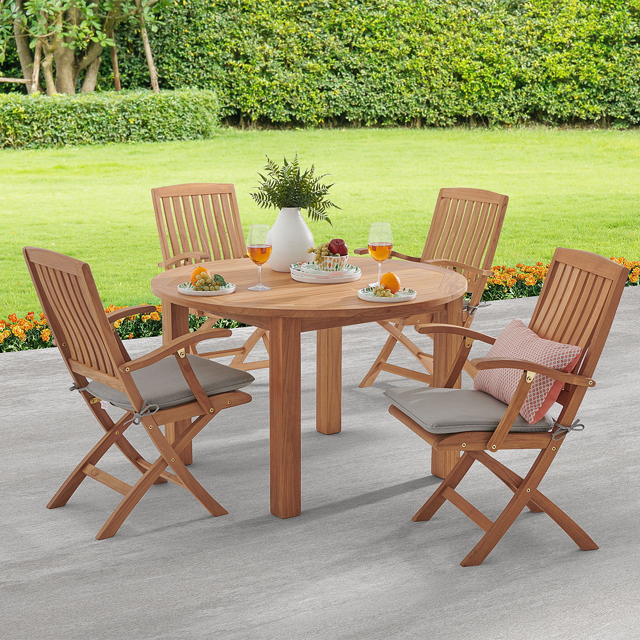 Wooden patio table with four chairs, surrounded by greenery and decorative plants.