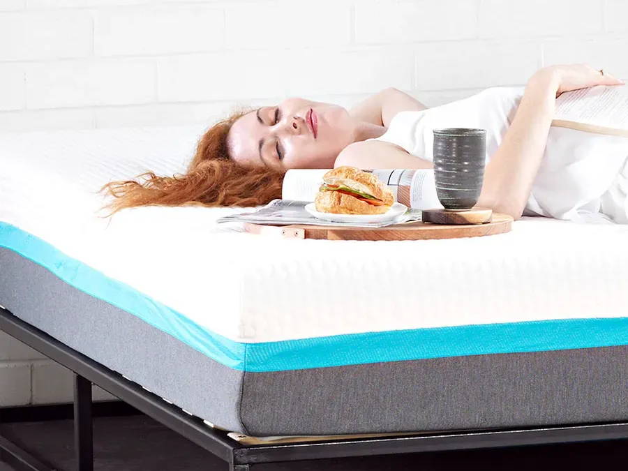 A woman sleeping on a Zeek Original Mattress, next to some breakfast in bed.