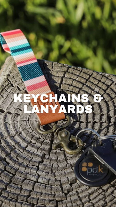 Keychains and lanyards on a wooden surface with green background.