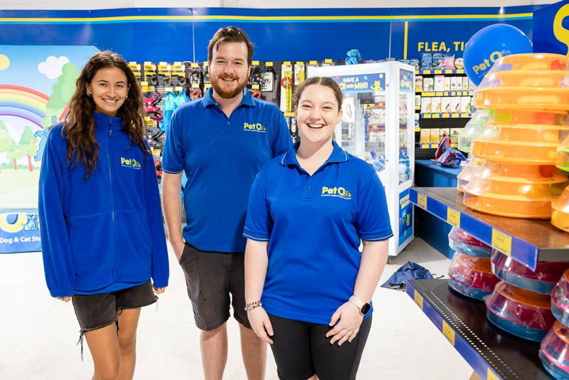 Three staff members at PetO Randwick standing next to shelves of pet supplies