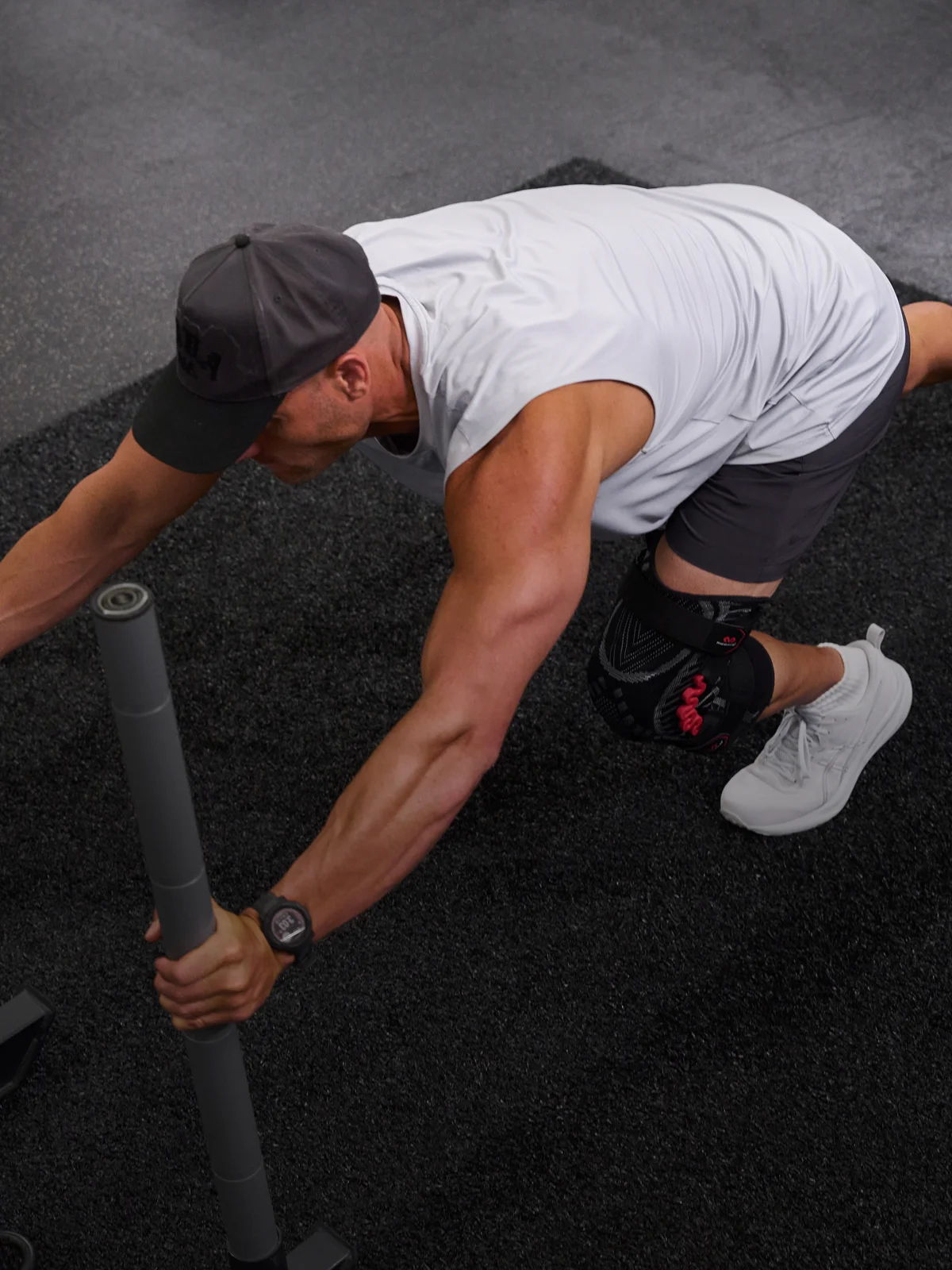 Person exercising on a mat, using a barbell, wearing a knee brace.