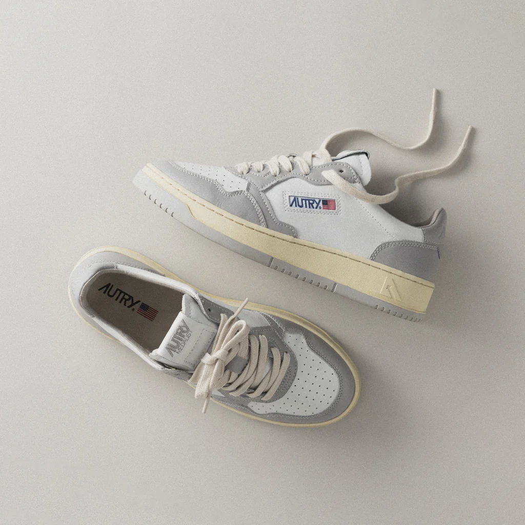 Pair of white sneakers with grey accents on a light background.