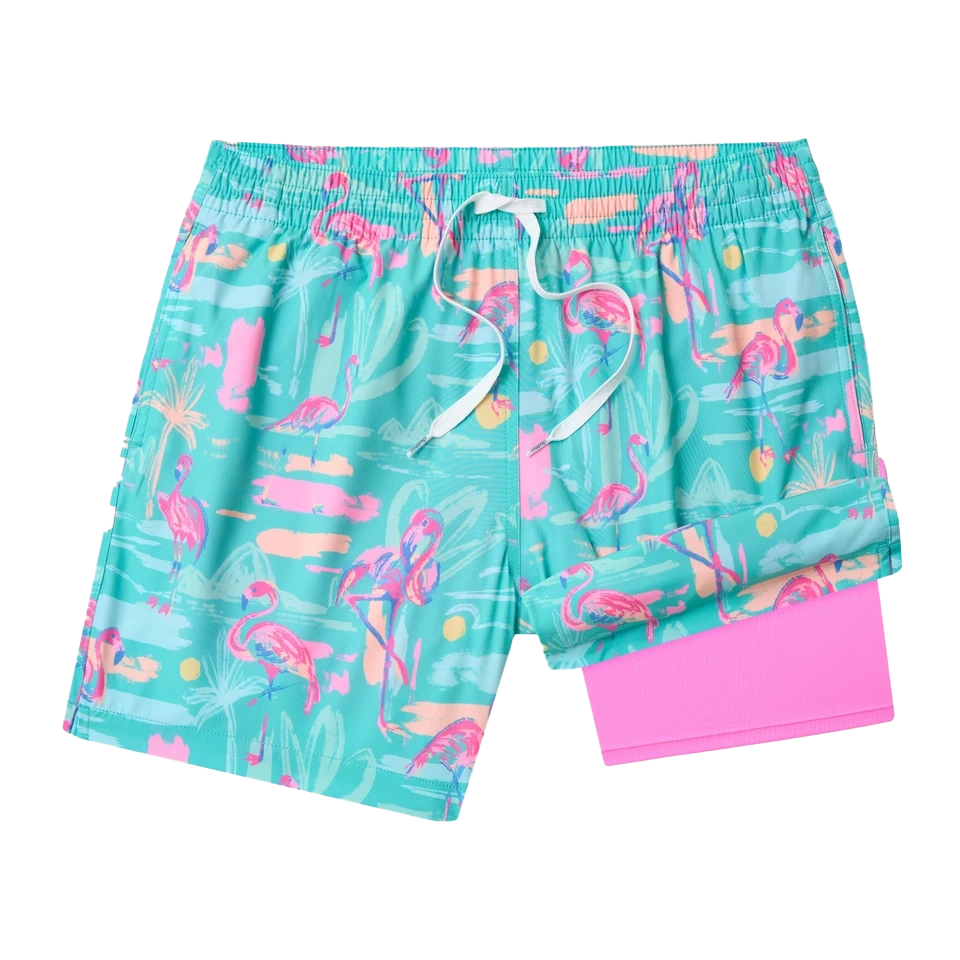 Turquoise swim trunks with pink flamingo pattern and pink lining.