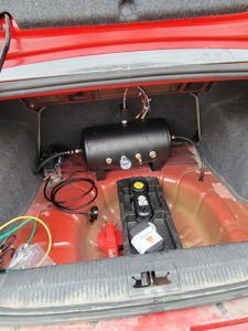 Black air tank and compressor mounted in car trunk