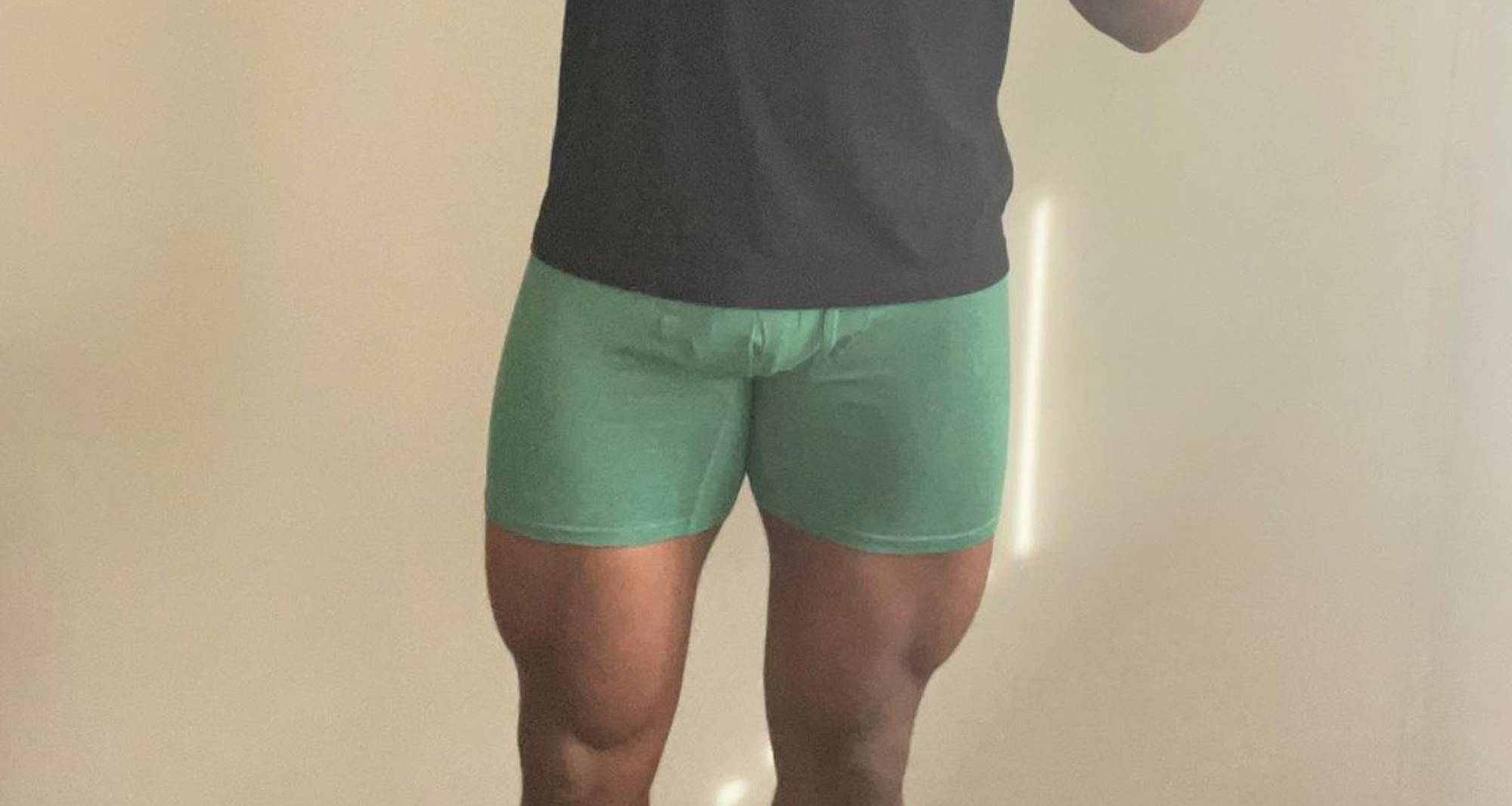 man wearing a black t-shirt and green boxer briefs holding up a peace sign and two other pairs of green undies