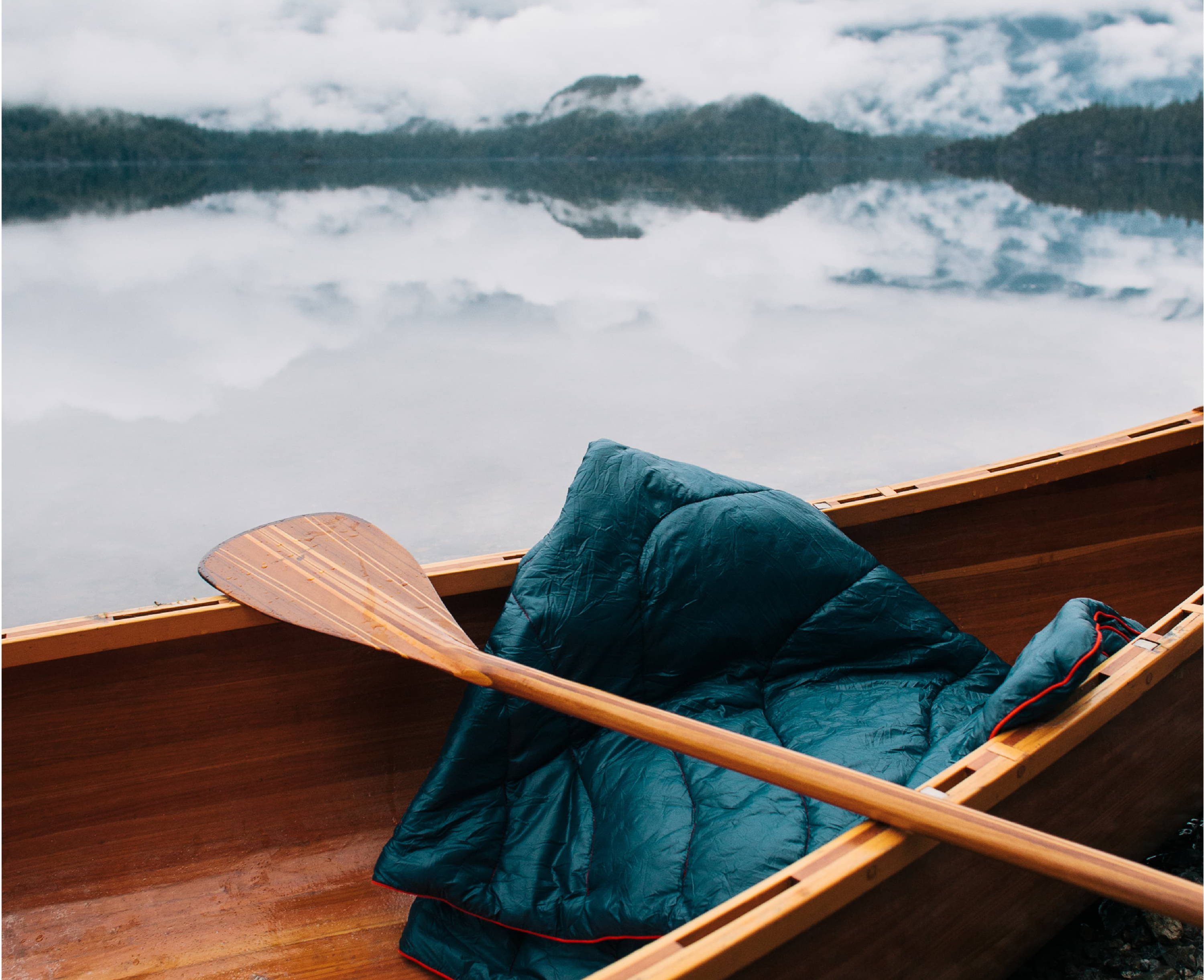 Rumpl Original Puffy Blanket In a Canoe floating on a lake