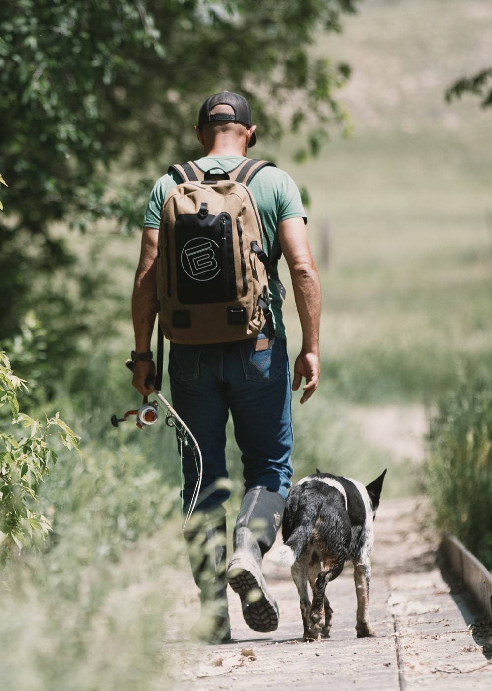 Man wearing the Last Cowboy Highwater Backpack and walking his dog