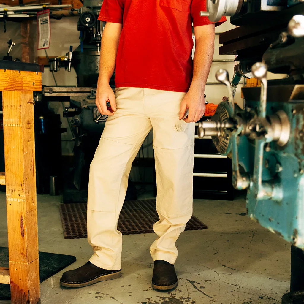 Person wearing a red shirt and beige pants in a workshop setting.