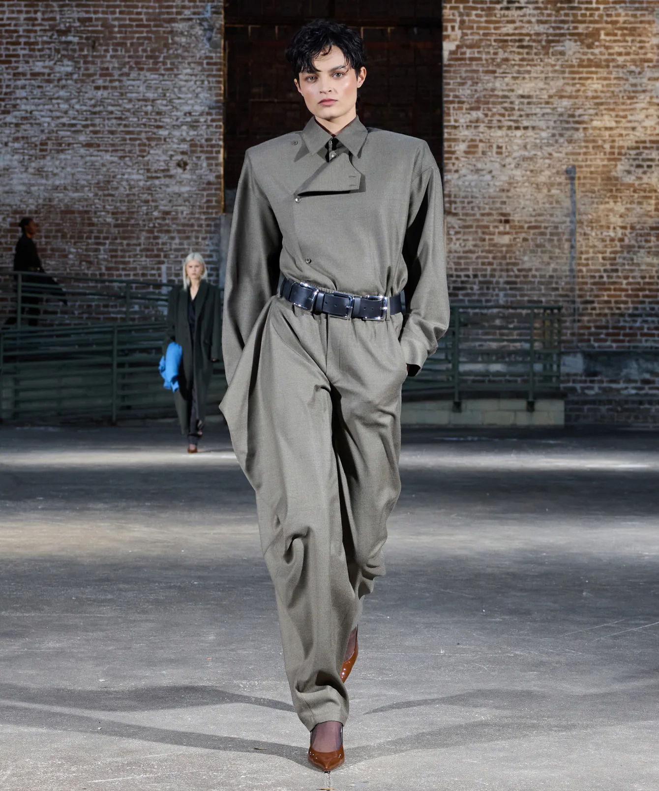 A model walks in a stylish gray outfit on a runway.