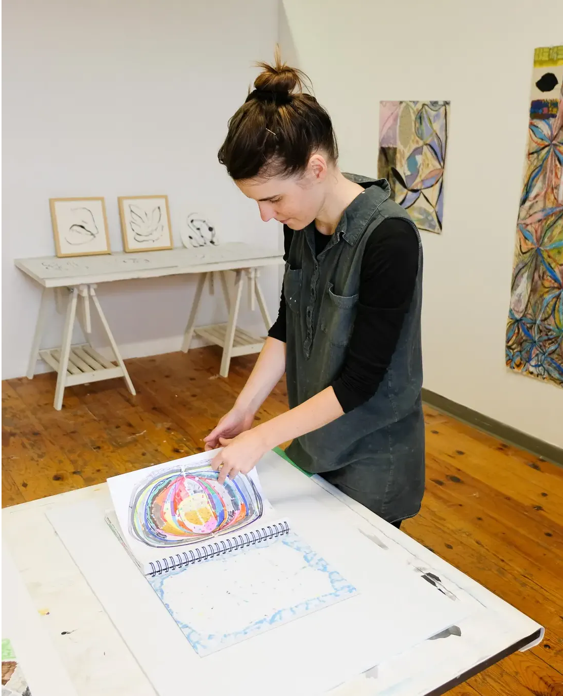 Rachel stands in her studio, flipping through her sketchbook. 