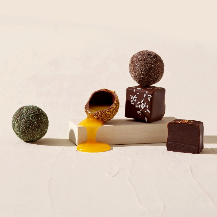 Assorted gourmet chocolates and truffles on a light background.
