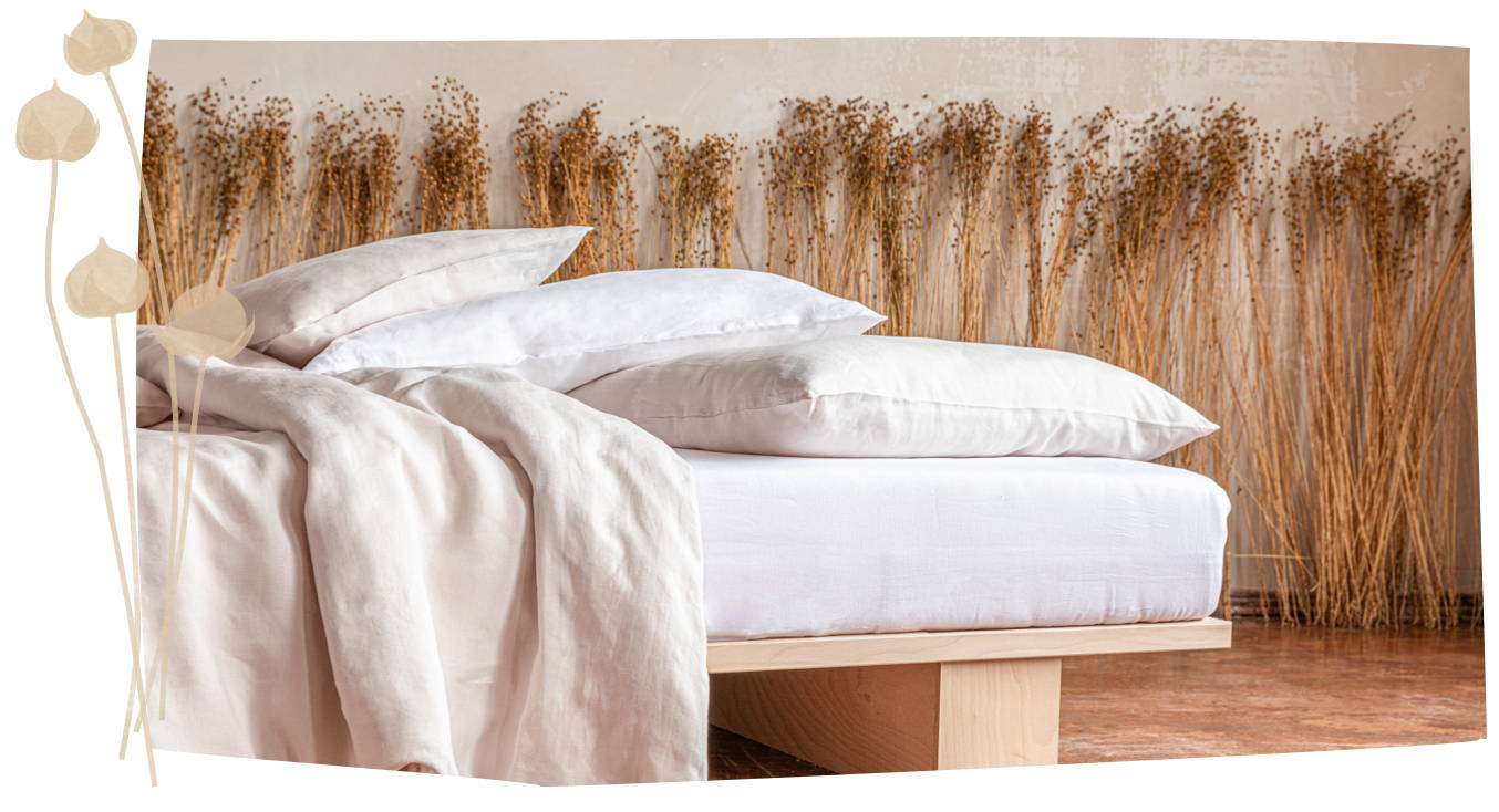 Ein Bett mit Leinen-Bettwäsche und Flachs im Hintergrund