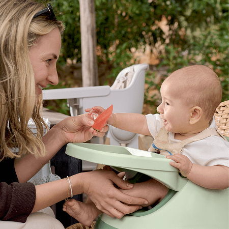 A mother and baby share a moment with a piece of fruit.