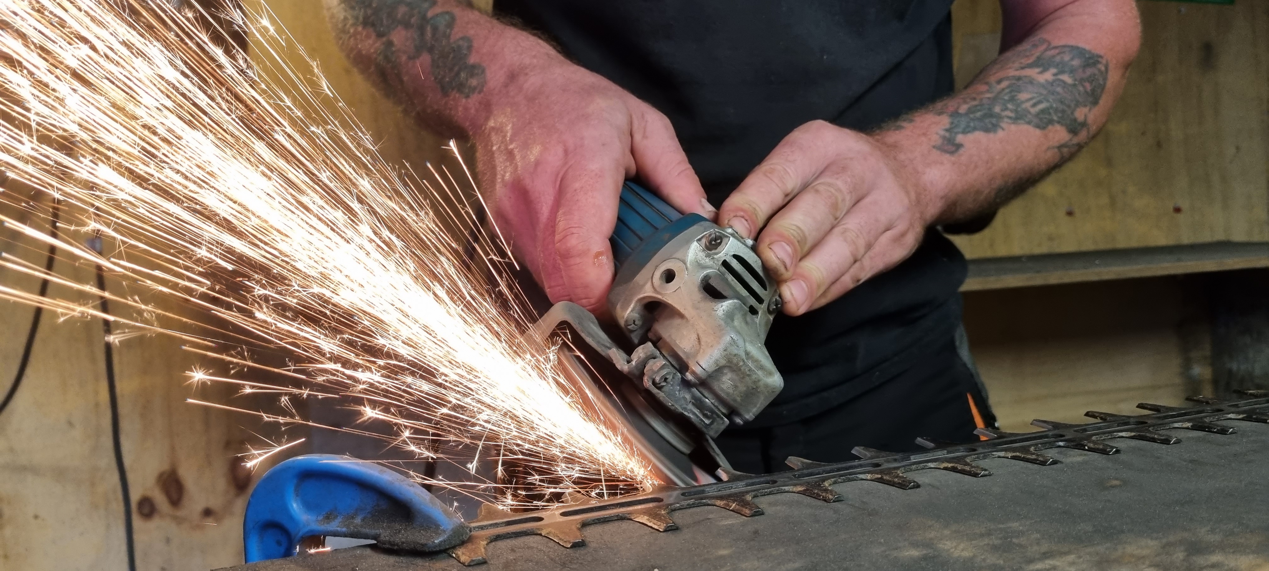 Person using a grinder, creating sparks on a metal surface.