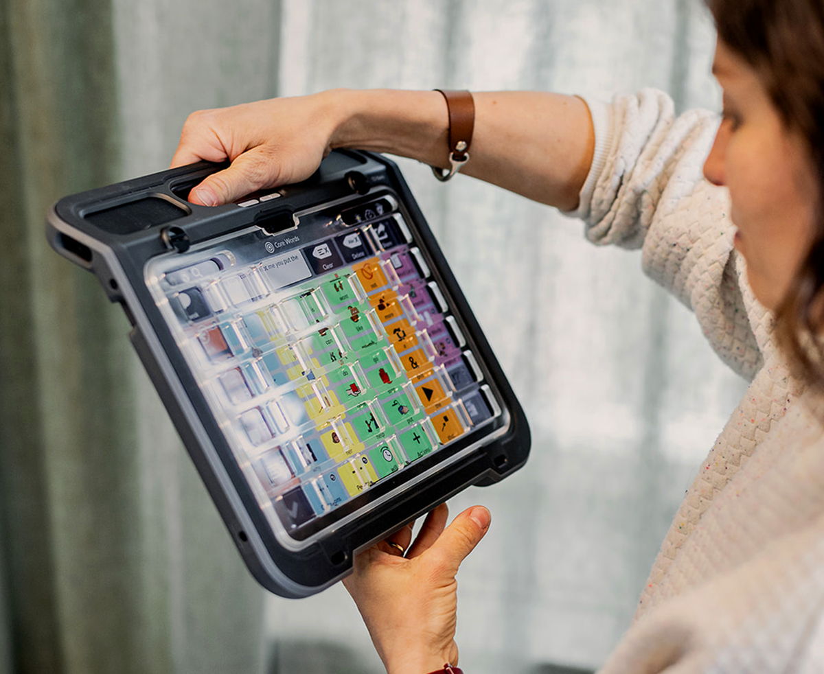 Woman holding up communication device with a keyguard attached to the screen