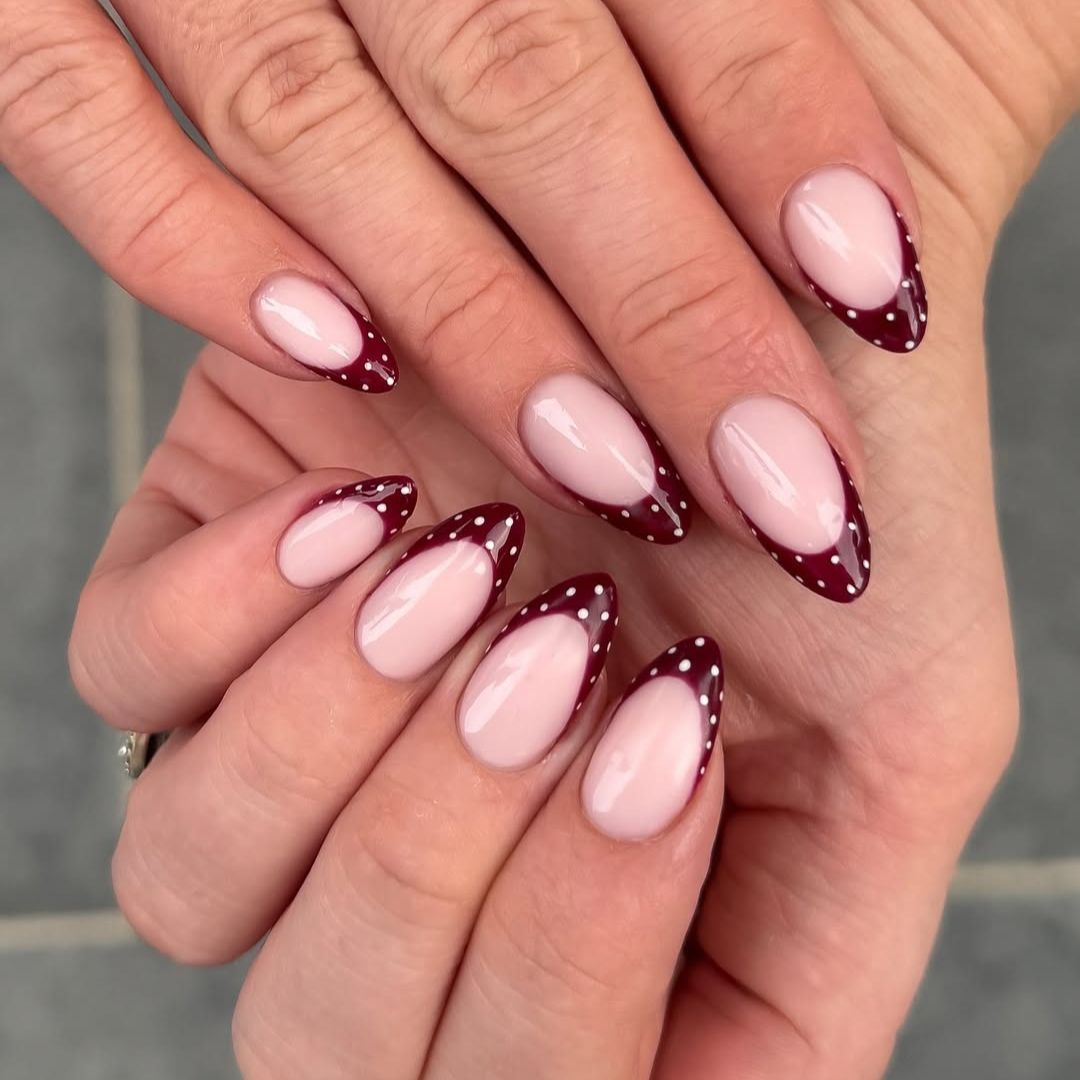 Burgundy and white polka-dot French manicured nails with a glossy finish.