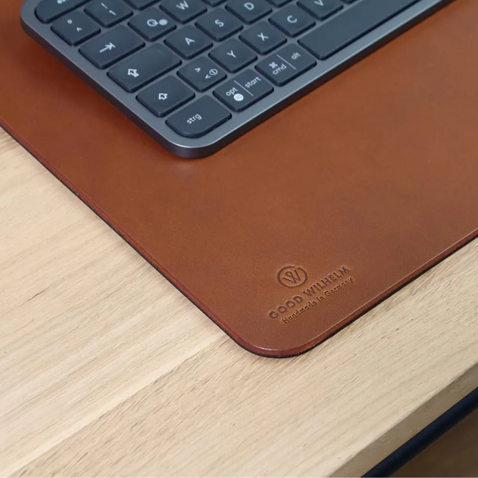Nahaufnahme des Goodwilhelm Logos auf Schreibtischunterlage KARL mit Tastatur