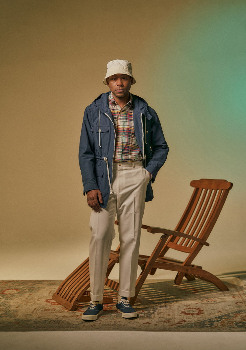 Person in casual outfit stands next to a wooden chair on a rug.