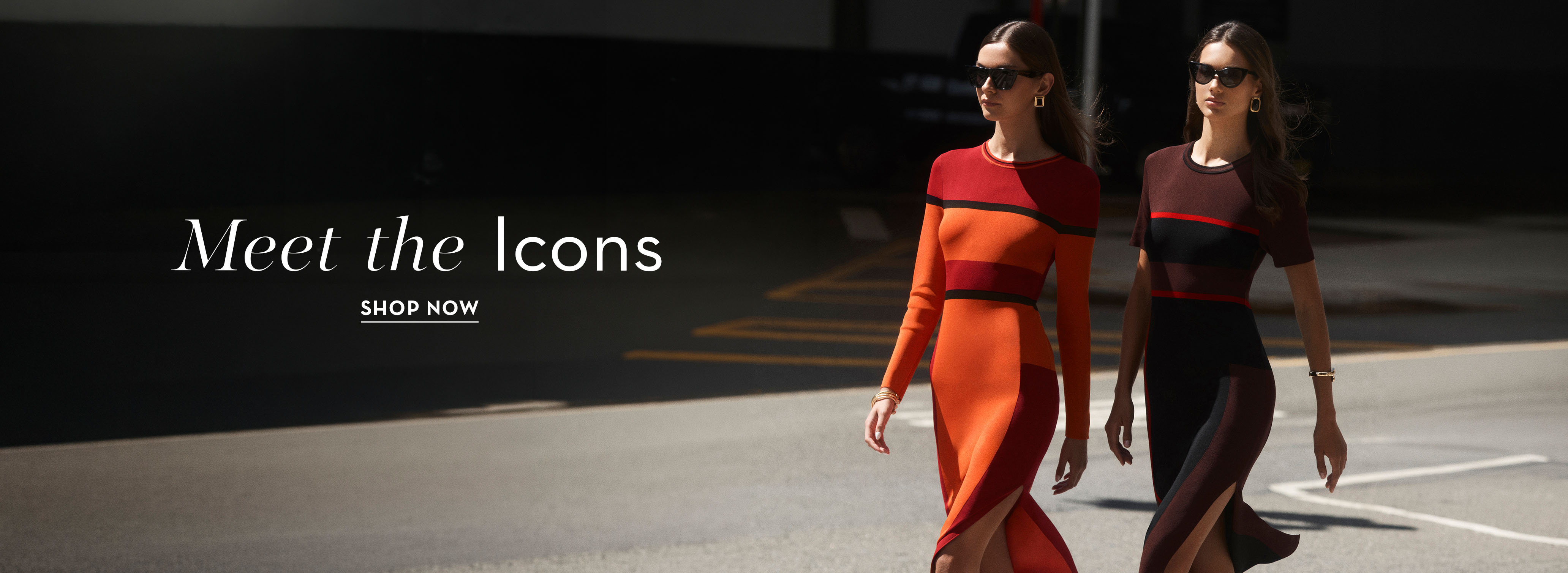Two women walking in stylish dresses on a city street.