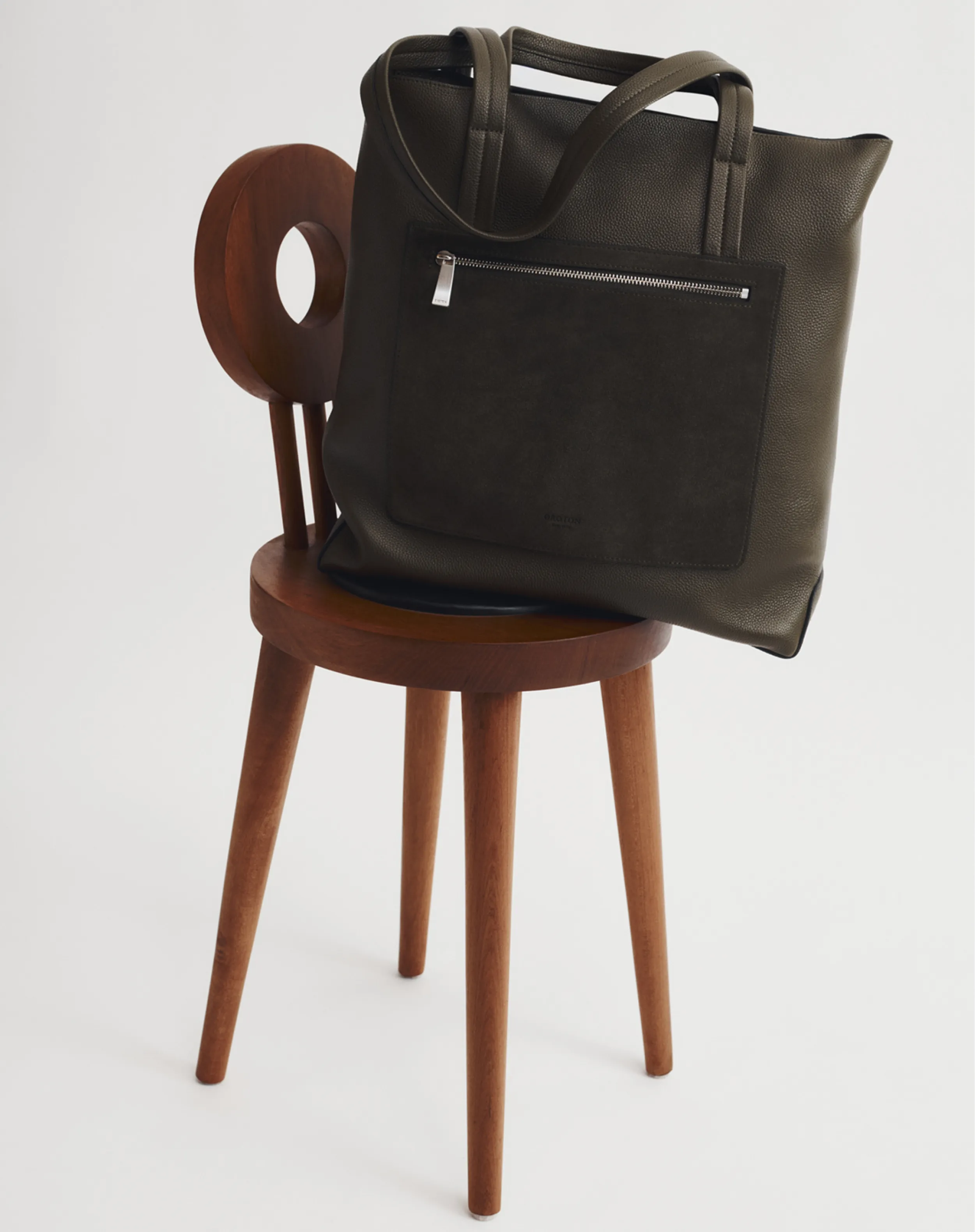 A dark bag resting on a wooden chair.