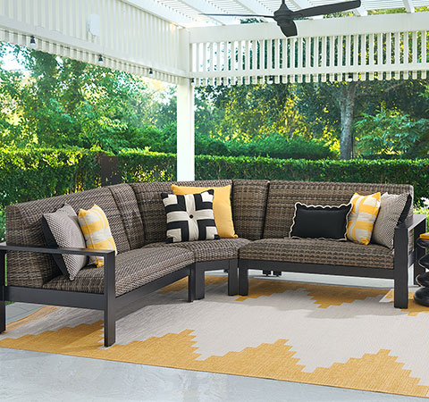 Outdoor seating area with a sectional couch and decorative pillows.