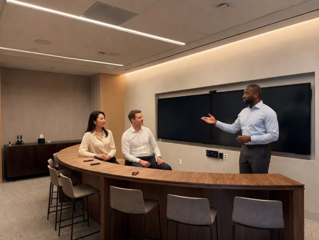 Three people in a modern conference room discussing at a curved table.