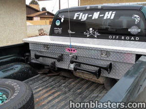 Dual black train horns mounted to a diamond-plate toolbox in the truck bed