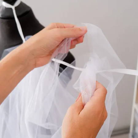 Two hands showing how to pull the strips of tulle fabric through