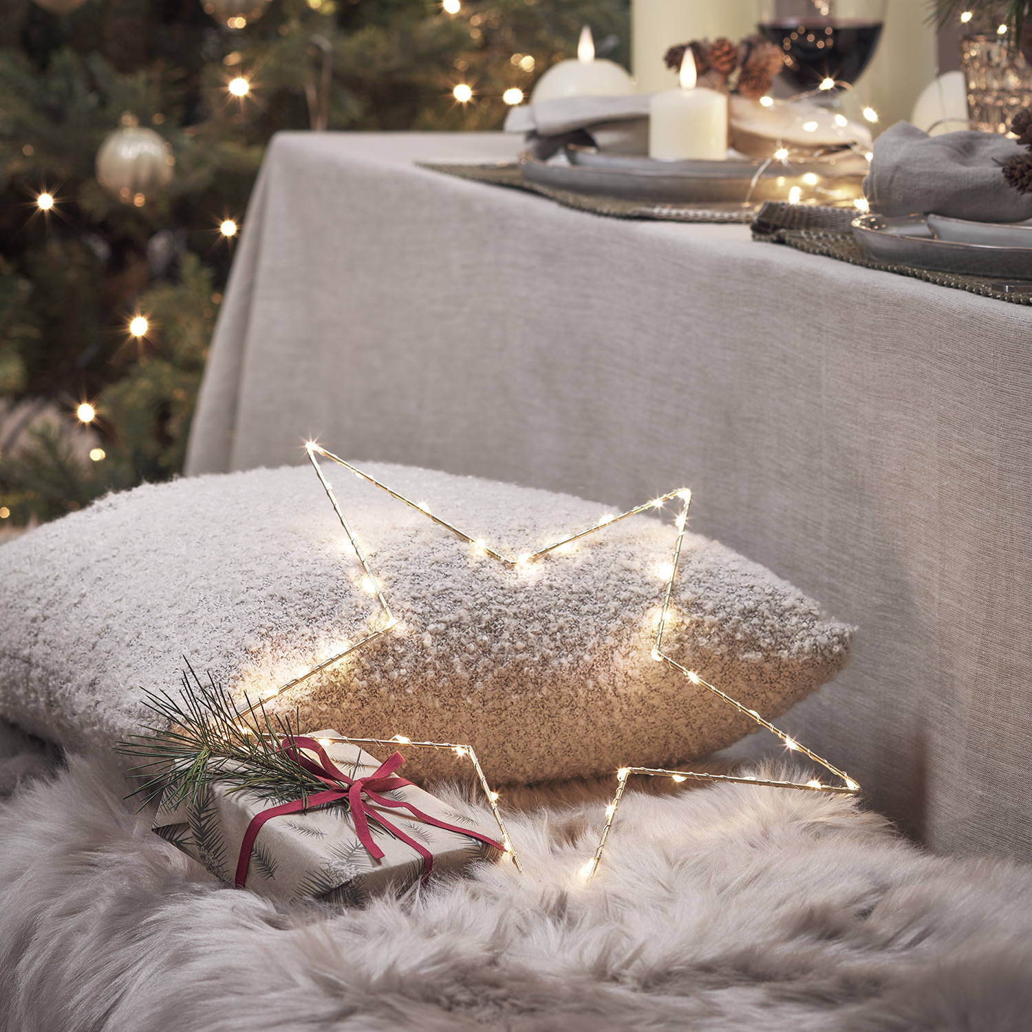 A cosy blanket and cushion lining a dining table bench complete with LED star lights and presents